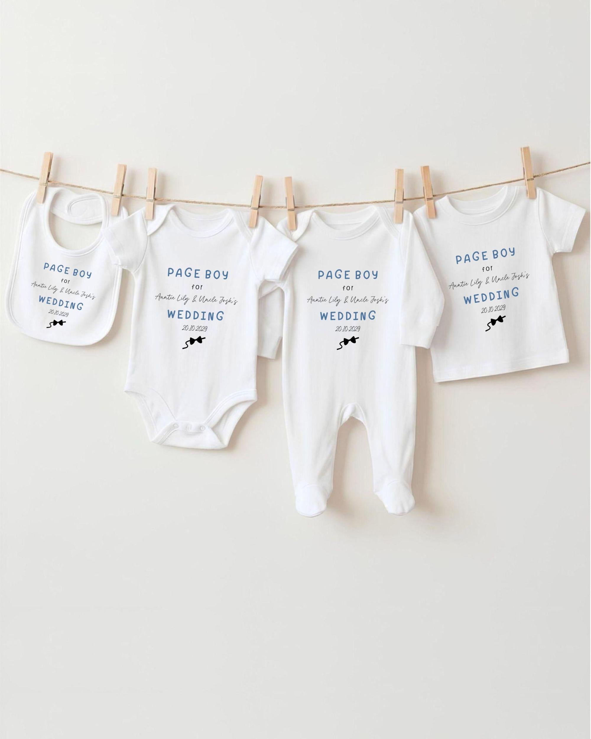 A row of four white baby clothes, including onesies and pajamas, hanging on a clothesline.