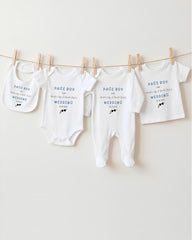 A row of four white baby clothes, including onesies and pajamas, hanging on a clothesline.