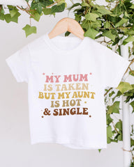 A white t-shirt with a humorous text printed on it, hanging on a wooden hanger.