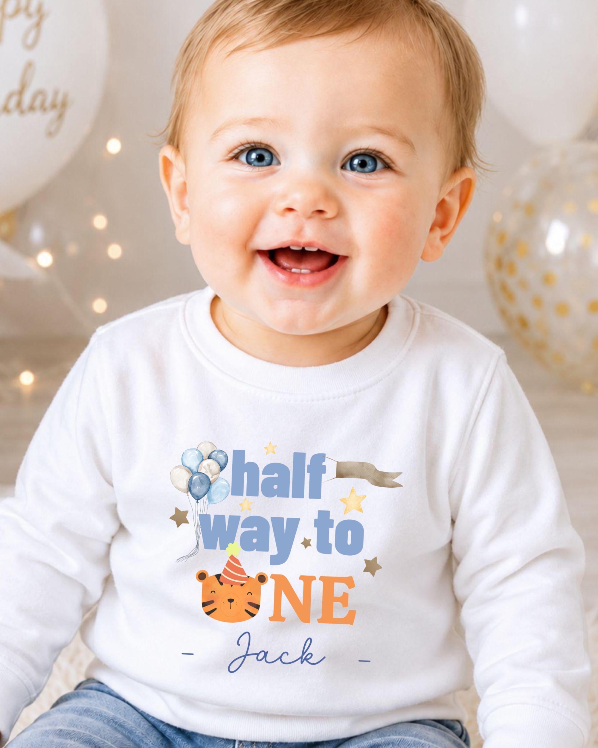 A smiling baby boy wearing a white shirt with a birthday message printed on it.