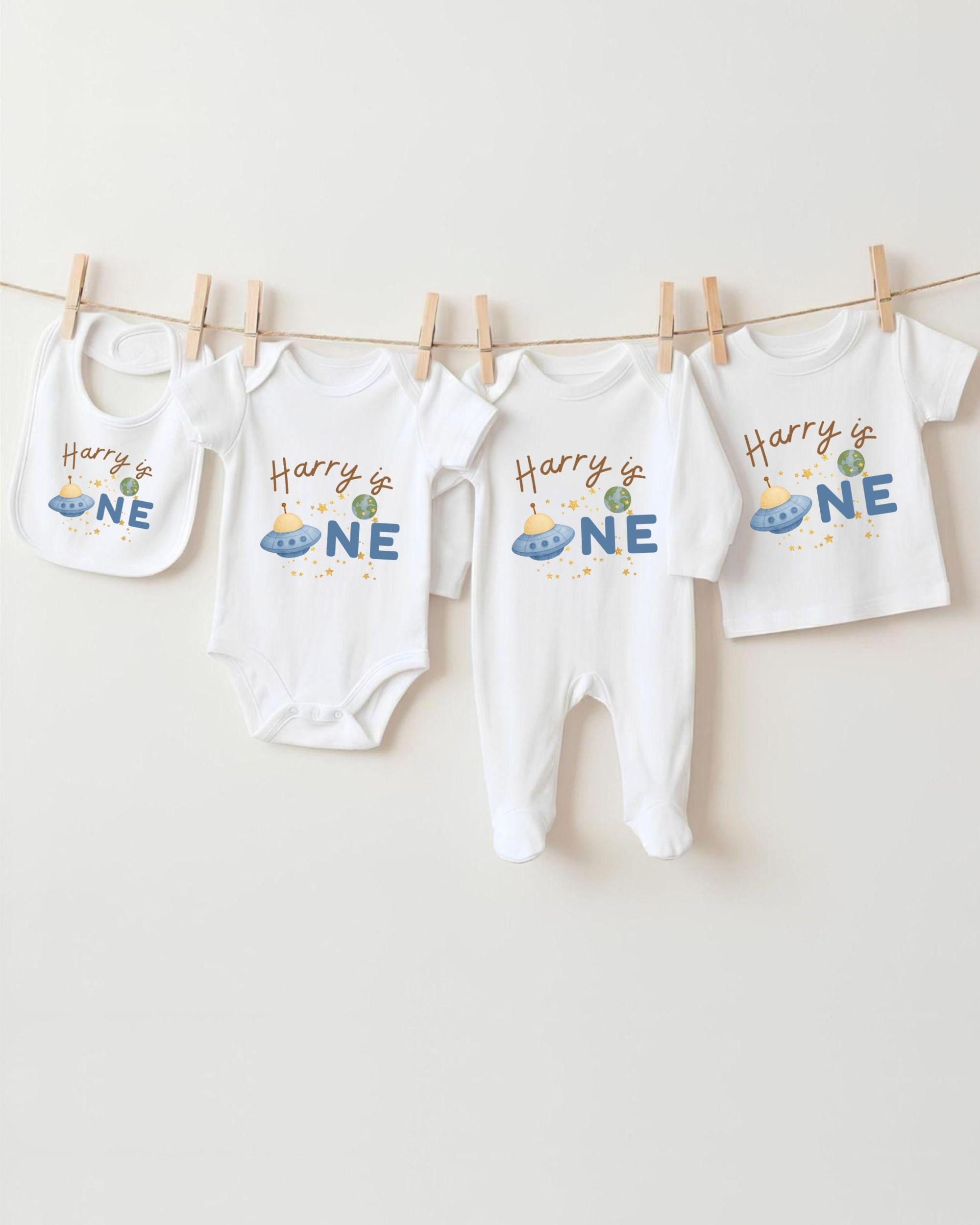 A collection of white baby clothes, including onesies and pajamas, hanging on a clothesline.