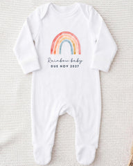 A white onesie with a rainbow graphic and the text "Rainbow baby due novely 2017" printed on it.