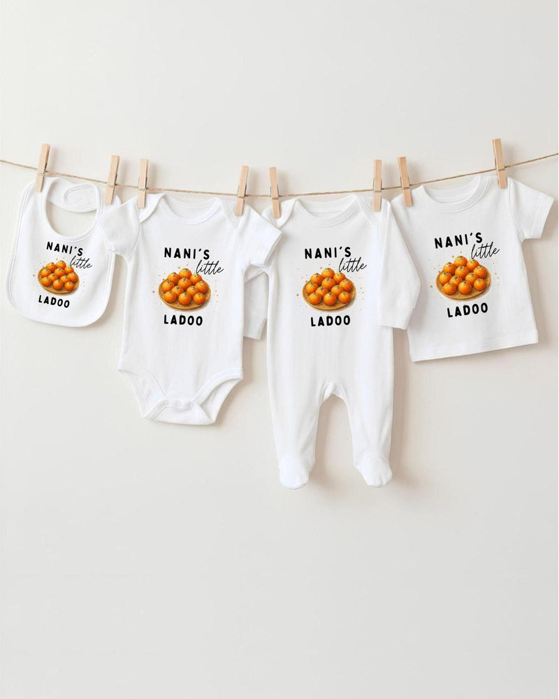 A row of white baby clothes with the text "NANI'S LITTLE LADOO" printed on them, along with an image of oranges.