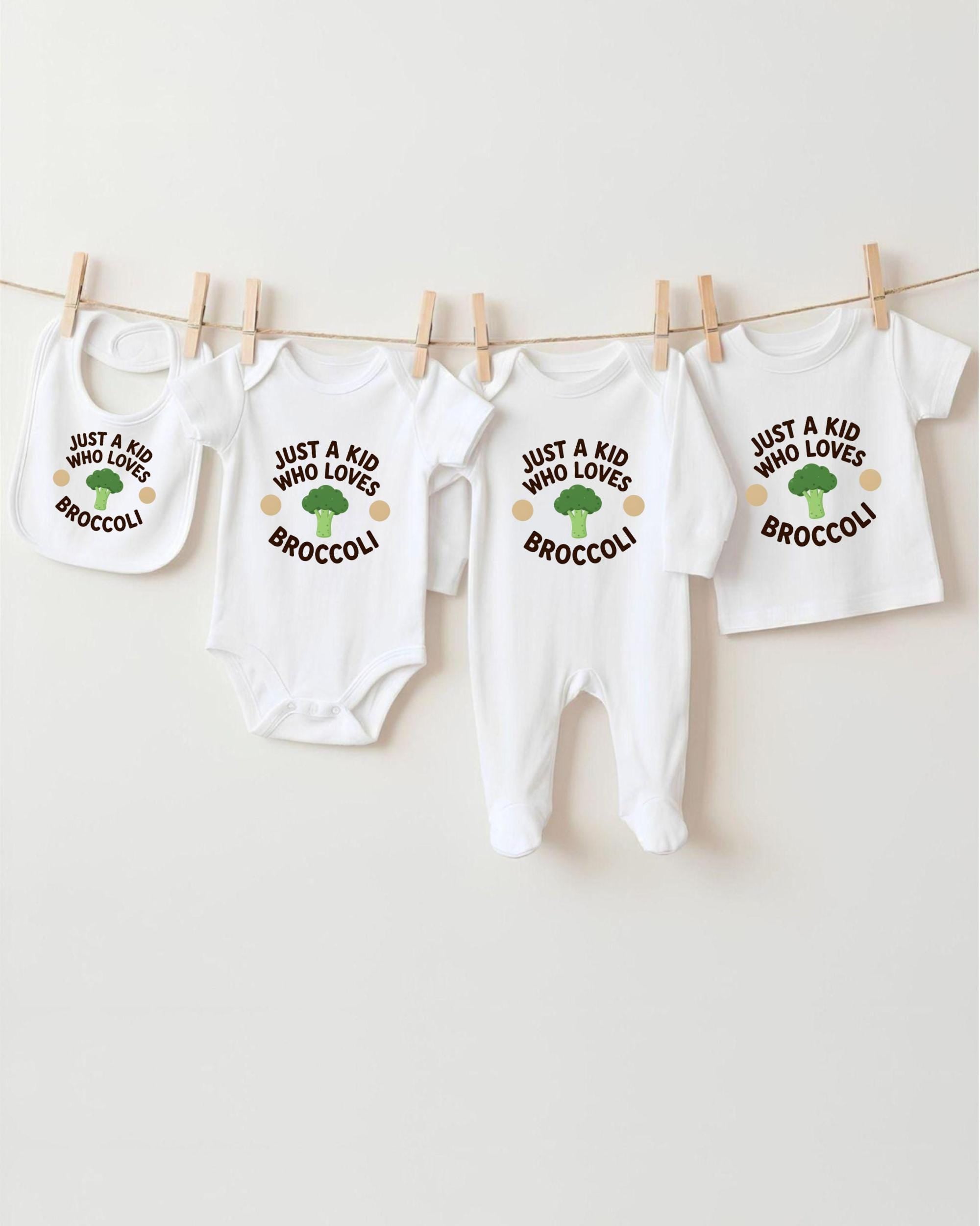 A row of four white baby clothes with the text "Just a kid who loves broccoli" printed on them, hanging on a clothesline.