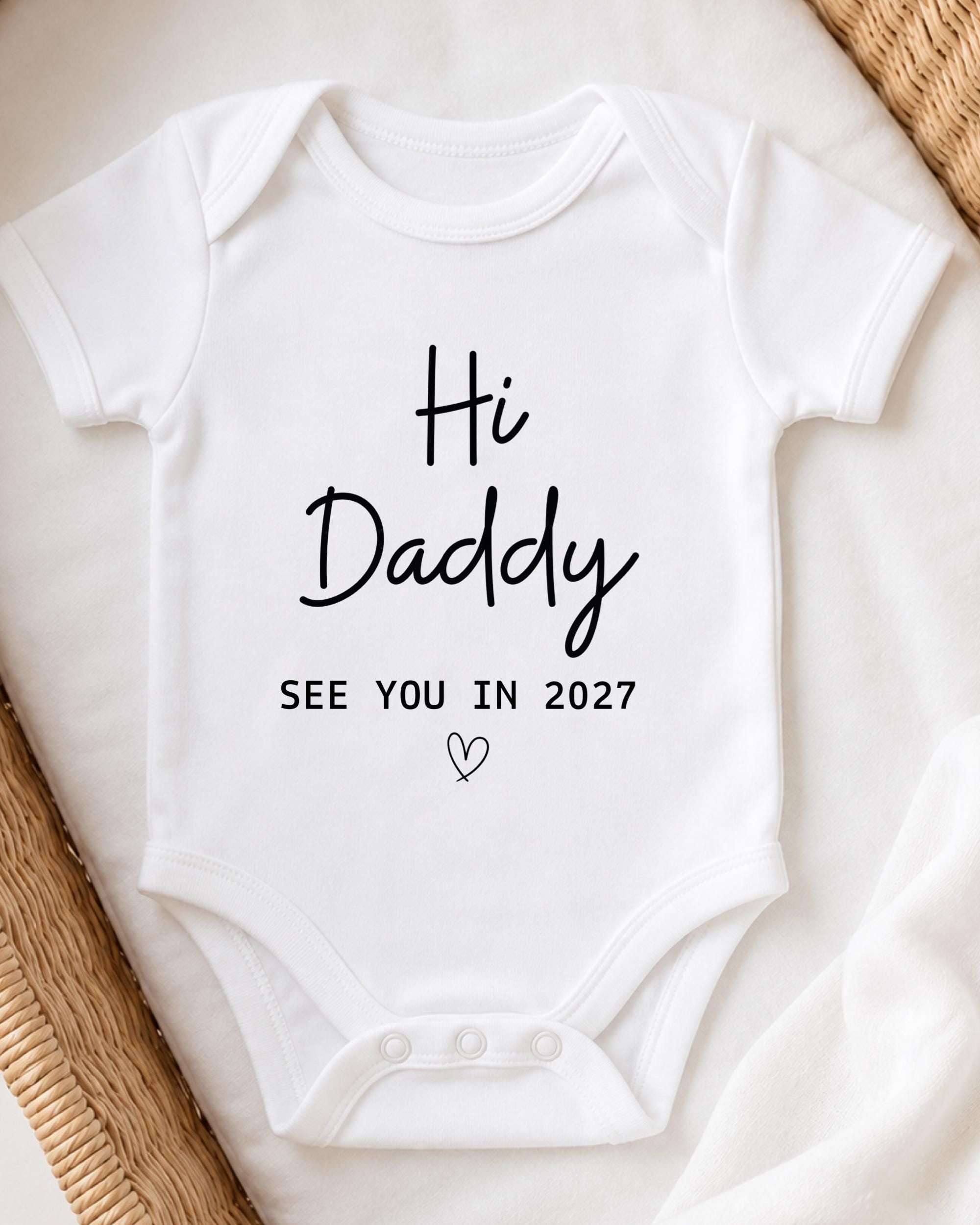 A white baby onesie with the text "Hi Daddy See You in 2027" printed on it.