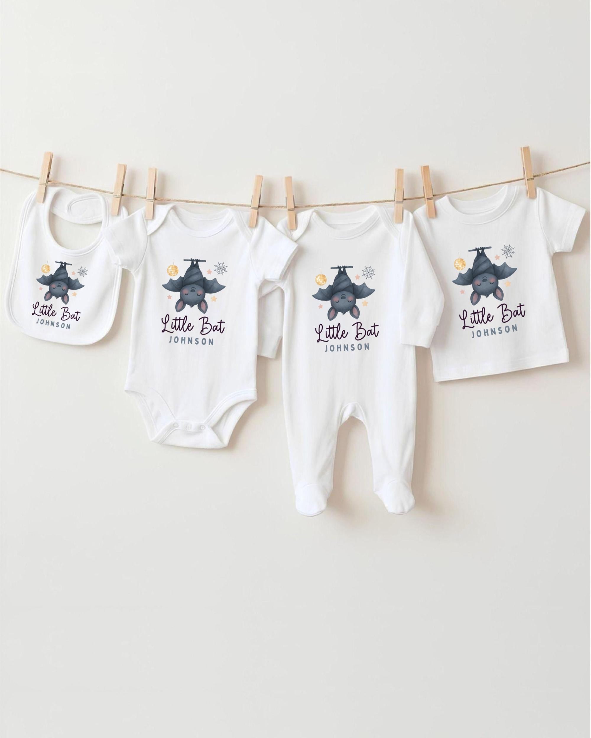 A collection of baby clothes, including onesies and bibs, hanging on a clothesline.