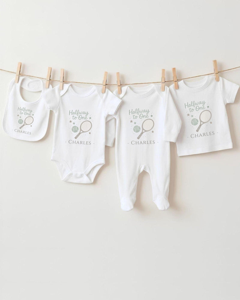 A row of white baby clothes, including onesies and bibs, hanging on a clothesline.
