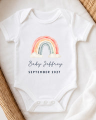 A white onesie with a rainbow graphic and the text "Baby Jeffrey September 2027" printed on it.
