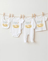 A collection of baby clothes and bibs hanging on a clothesline, featuring religious text and illustrations.