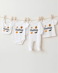 A collection of white baby clothes, including onesies and bibs, hanging on a clothesline.