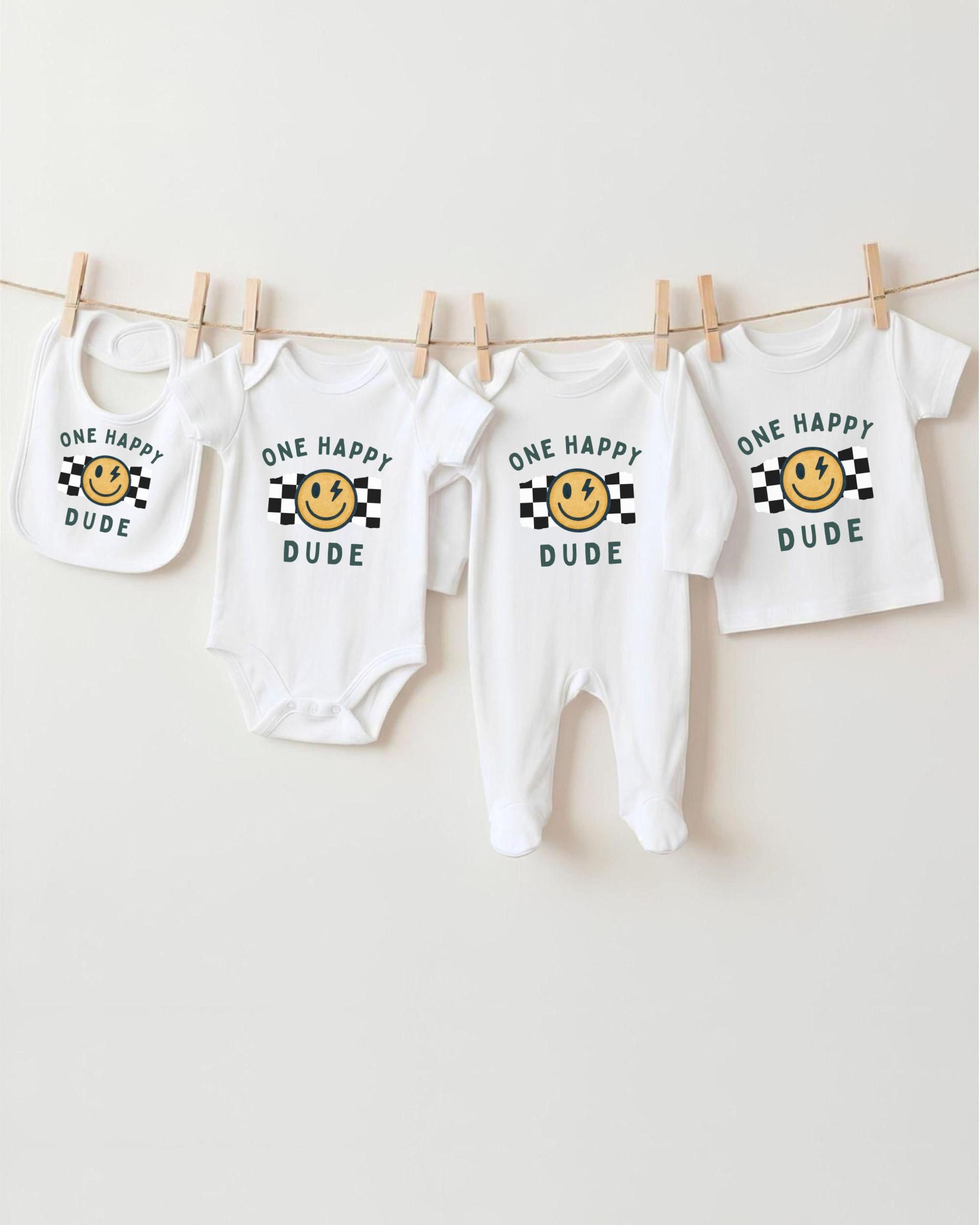 A collection of baby clothes, including onesies and bibs, hanging on a clothesline.