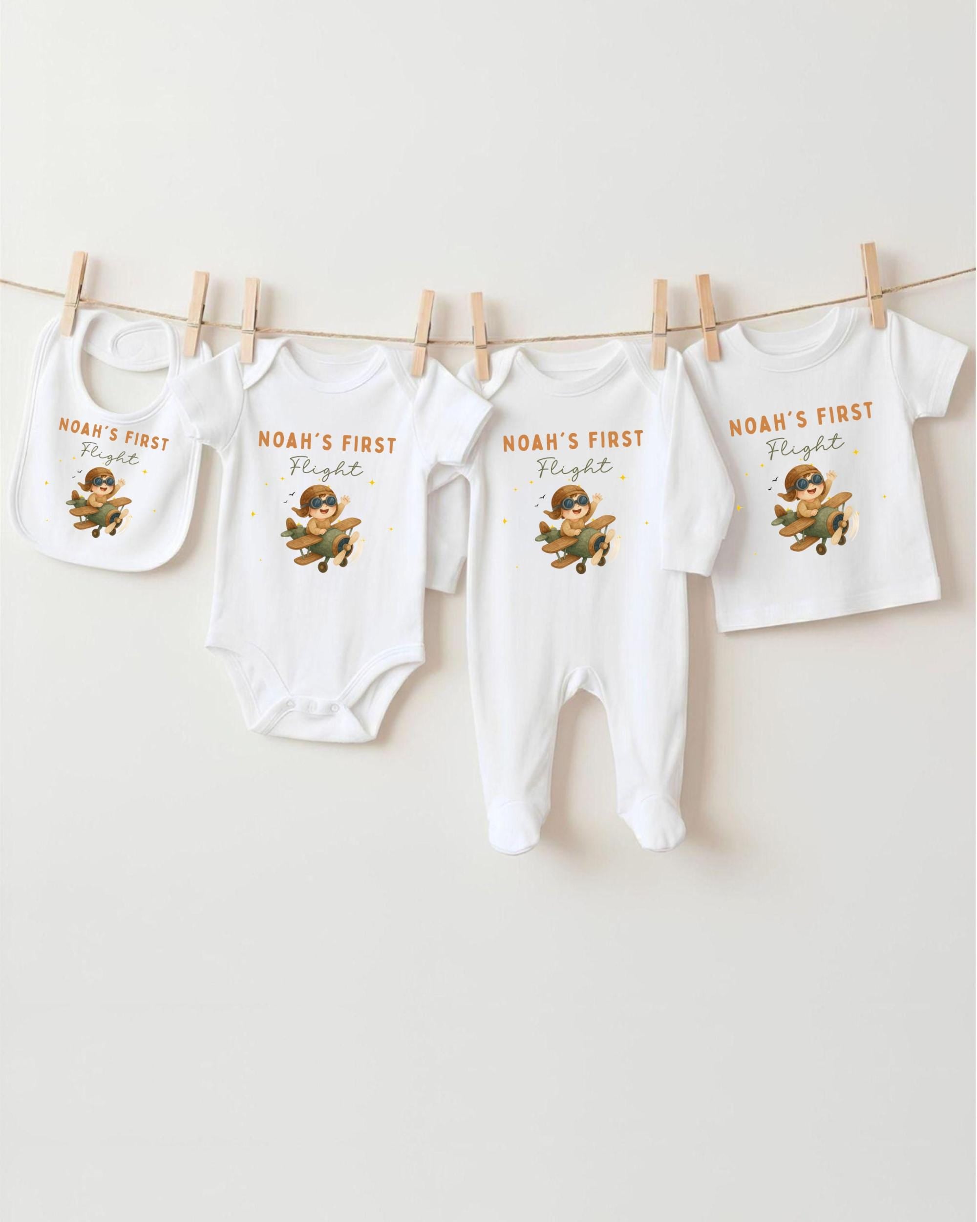 A collection of baby clothes, including onesies and bibs, hanging on a clothesline.