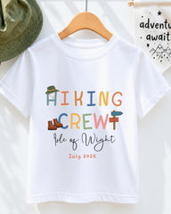 A white t-shirt with colorful text and illustrations, including the words "Hiking Crew" and " Isle of Wight" along with the date "July 2023".