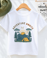 A white t-shirt with a graphic design depicting a camping scene with mountains, pine trees, and a tent, along with the text "Adventure Awaits" printed on it.