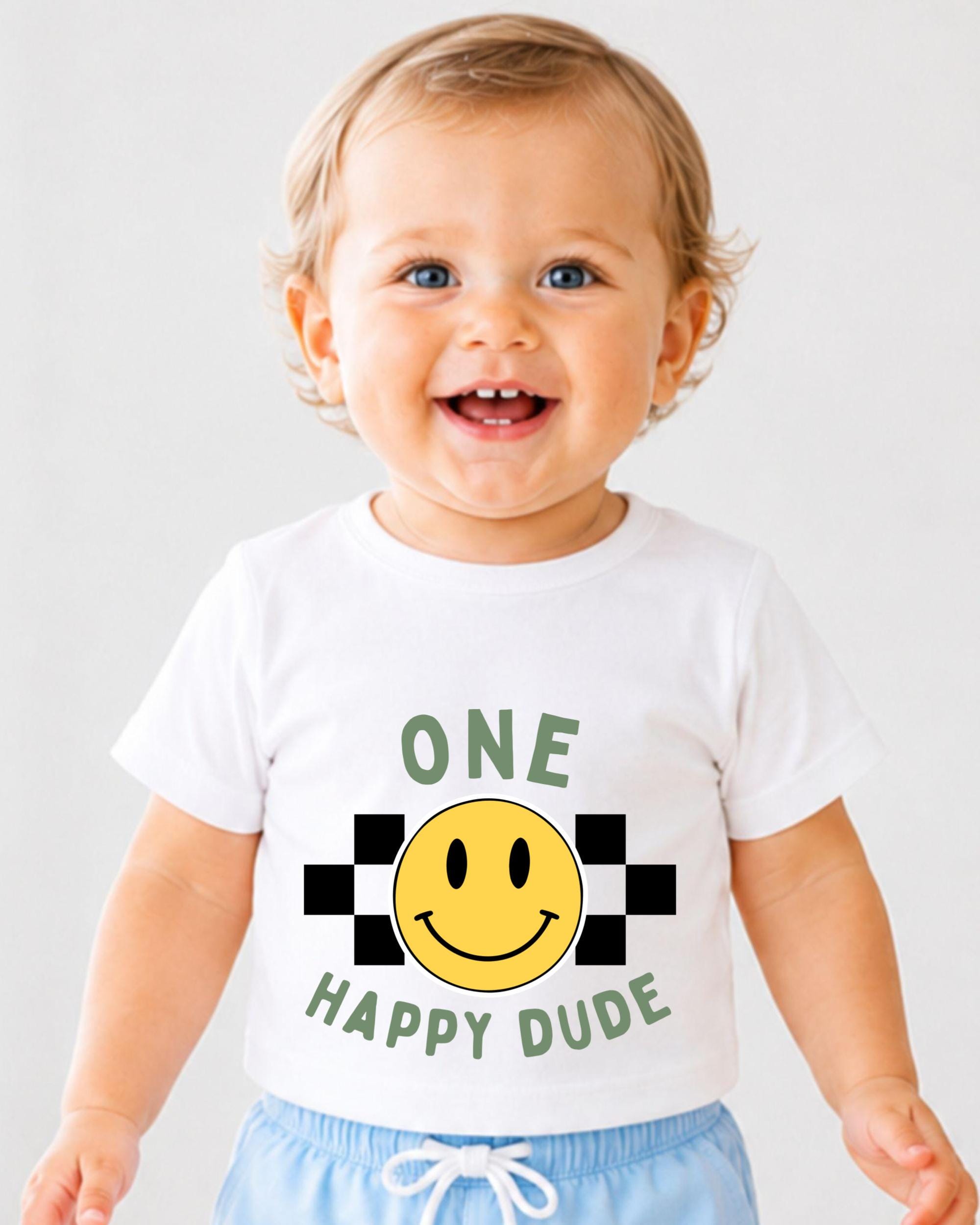 A smiling baby wearing a white t-shirt with a yellow smiley face and the text "ONE HAPPY DUDE" printed on it.