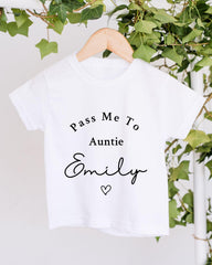 A white t-shirt with the text "Pass Me To Auntie Emily" printed on it, hanging on a wooden hanger.