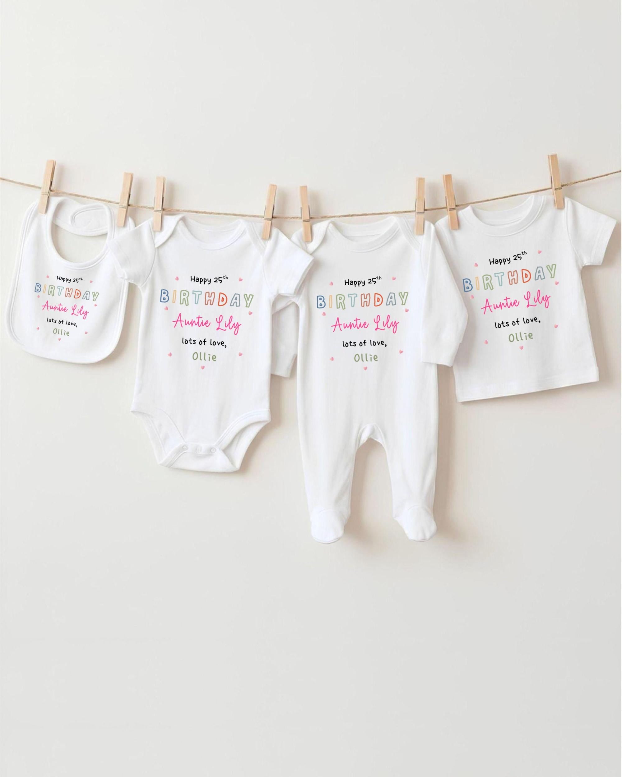 A row of four white baby clothes, including onesies and bibs, hanging on a clothesline.