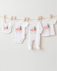 A collection of four white baby clothes, including onesies and bibs, hanging on a clothesline.