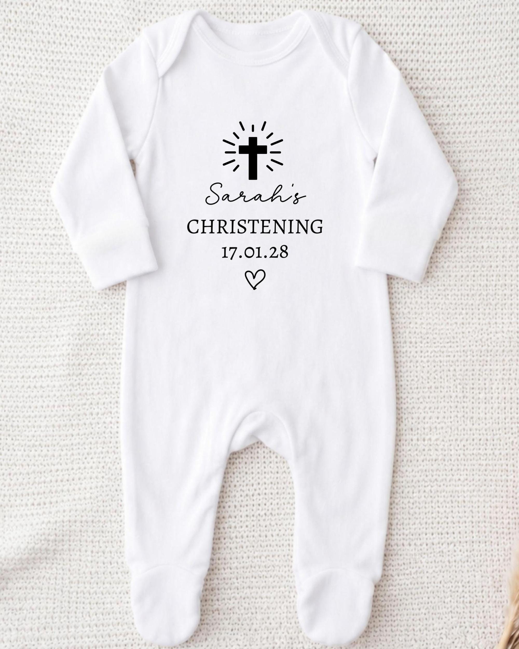 A white onesie with a black cross and text printed on it.