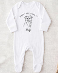 A white onesie with a black illustration of a dog and the text "LOVED & PROTECTED BY Hugo" printed on it.