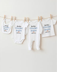 A row of white baby clothes with the text "Daddys Fishing Buddy Alexander" printed on them, hanging on a clothesline.