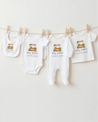A row of four white baby clothes, including onesies and bibs, hanging on a clothesline.