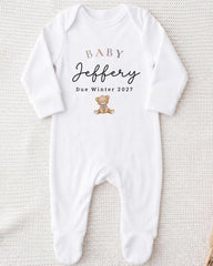 A white onesie with text and a teddy bear graphic printed on it.
