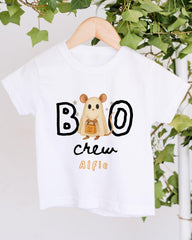 A white t-shirt with a cartoon mouse and the text "BOO" and "CREW AIFIE" printed on it, hanging on a wooden hanger.