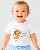 A smiling baby boy wearing a white t-shirt with a cartoon lion and the text "Happy Birthday Grandpa" printed on it.
