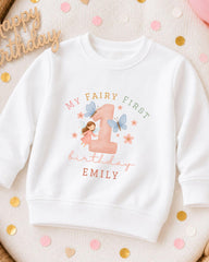 A white sweatshirt with a personalized design for a first birthday, featuring a fairy and the number 1.