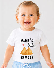 A smiling baby wearing a white t-shirt with a graphic design and text printed on it.