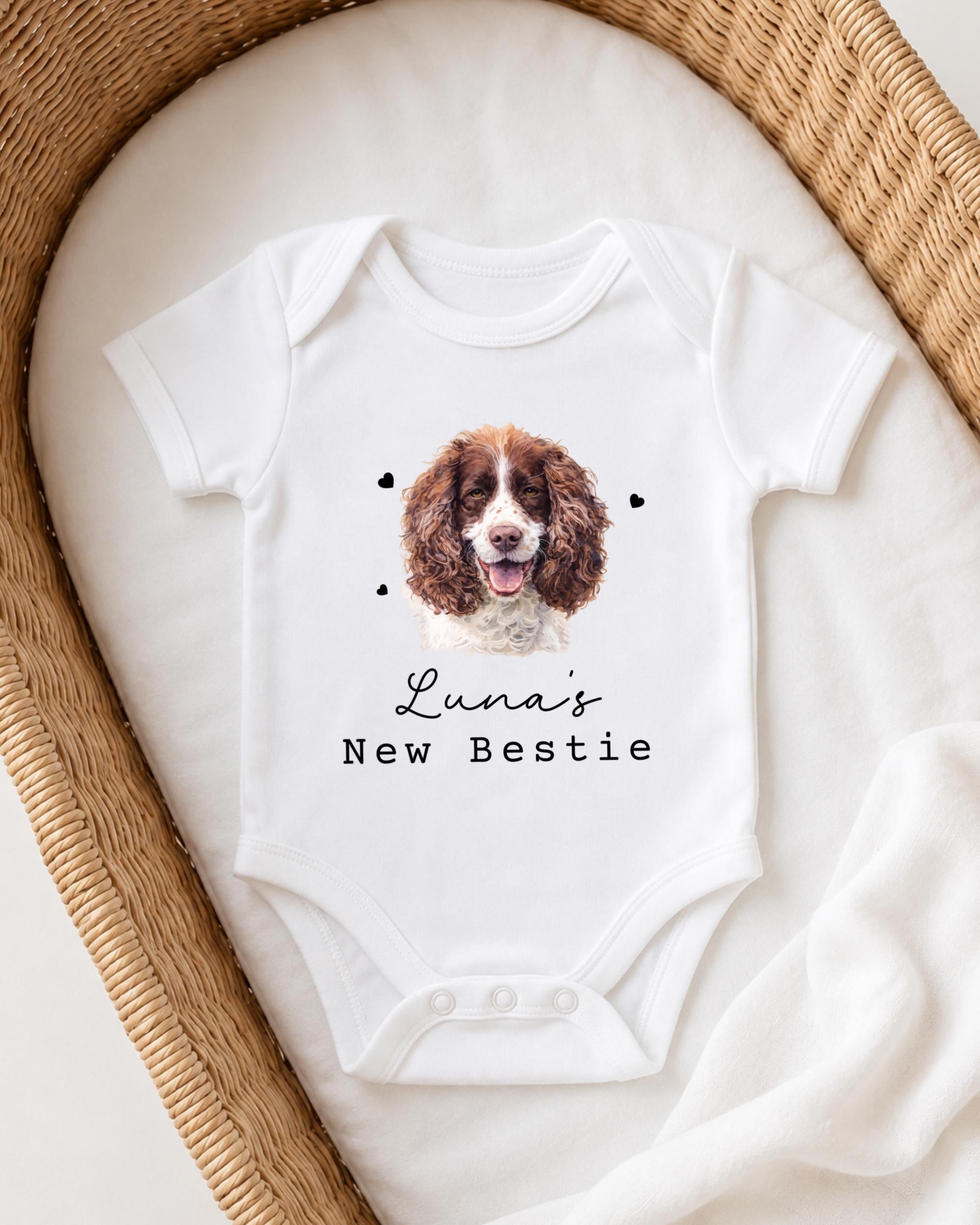 A white onesie with a picture of a brown and white dog on it, and the text "Luna's New Bestie" printed on it.