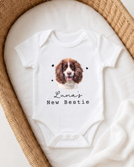 A white onesie with a picture of a brown and white dog on it, and the text "Luna's New Bestie" printed on it.