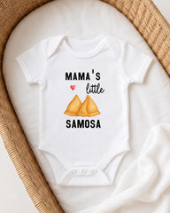 A white onesie with a printed design on it, featuring a heart symbol and the text "MAMA'S LITTLE SAMOSA".