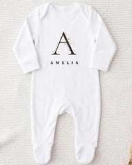 A white onesie with a monogrammed letter "A" and the name "Amelia" printed on it.