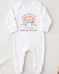 A white onesie with a graphic design on it, which says "Hand picked by Grandpa in Heaven Baby due Nov 2026".