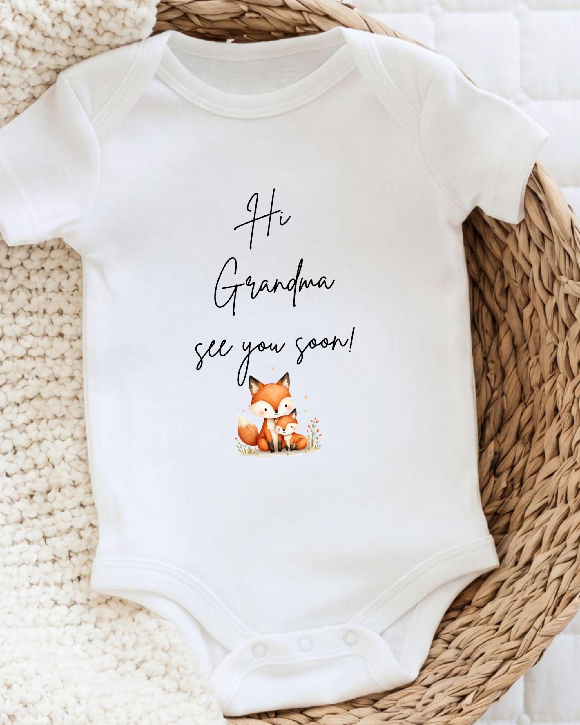 A white baby onesie with a cute illustration of a fox and the text "Hi Grandma, see you soon!" printed on it.