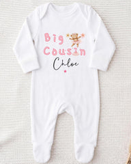 A white onesie with the text "Big Cousin Chloe" printed on it, along with a small illustration of a teddy bear.