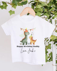 A white t-shirt with a graphic design featuring two cartoon dinosaurs wearing party hats, along with the text "Happy Birthday Daddy Love, Jack x" printed on it.