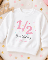A white sweatshirt with a birthday message printed on it, surrounded by confetti.