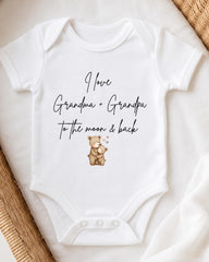A white baby onesie with a printed message that reads "I love Grandma + Grandpa to the moon & back".