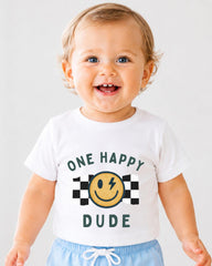 A smiling baby wearing a white t-shirt with a graphic design and text.