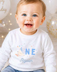 A smiling baby boy wearing a white shirt with a personalized name and birthday message.