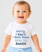 A smiling baby wearing a white t-shirt with text that says "Sorry, I Can't I Have Plans With My Auntie".