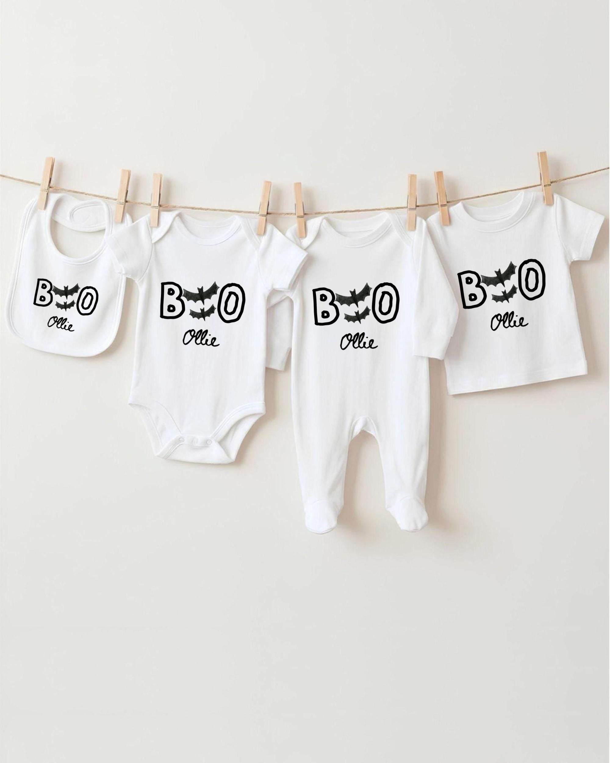 A collection of white baby clothes, including onesies and bibs, hanging on a clothesline.