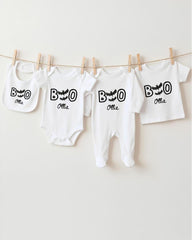 A collection of white baby clothes, including onesies and bibs, hanging on a clothesline.