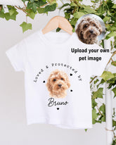 A white t-shirt with a printed image of a dog's face and the text "Loved & protected by Bruno" printed on it.