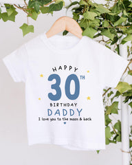 A white t-shirt with a birthday message printed on it, hanging on a wooden hanger.
