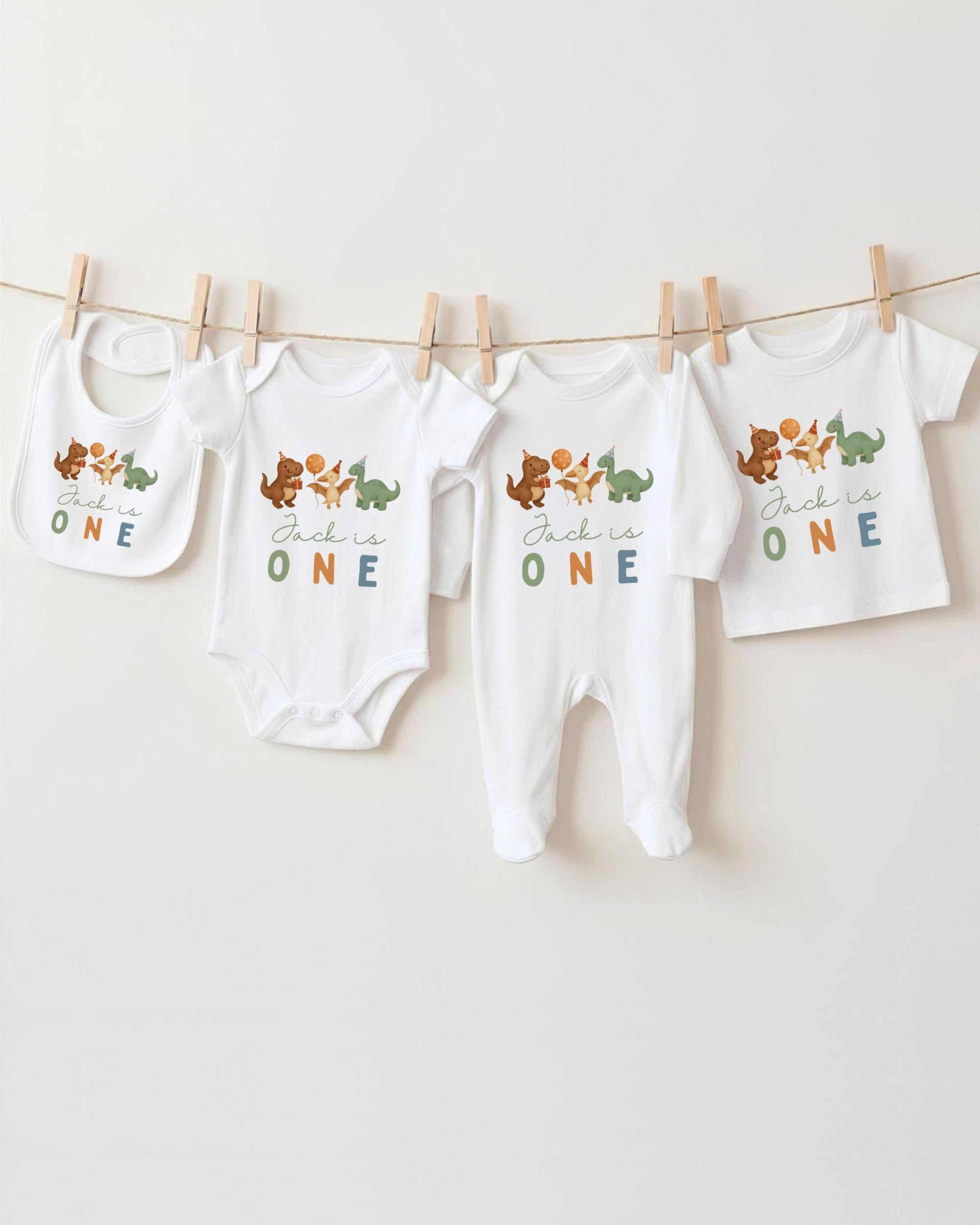 A collection of baby clothes, including onesies and pajamas, hanging on a clothesline.