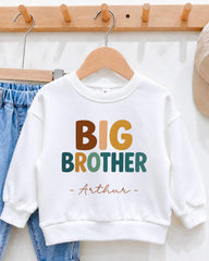 A white sweatshirt with the text "BIG BROTHER - Arthur" printed on it, hanging on a wooden hanger.